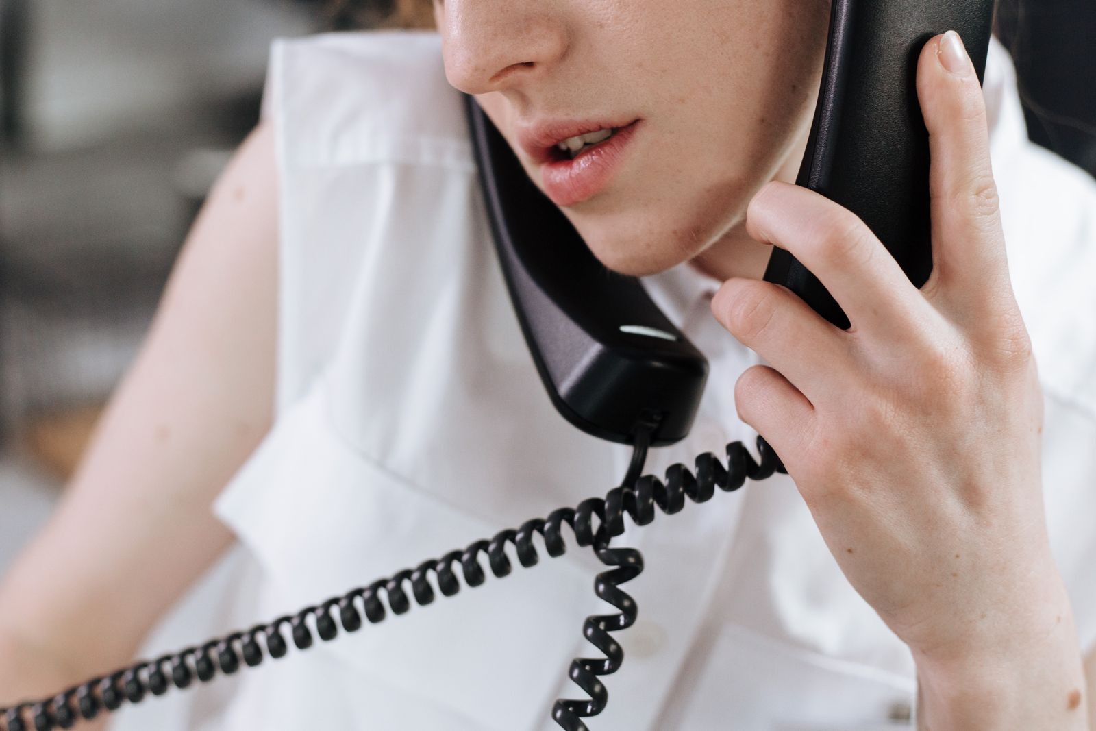 A person speaking on a desk telephone